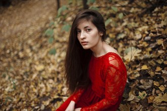 Caucasian woman sitting in autumn leaves