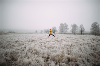 Caucasian woman leaping in snowy field