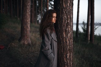 Caucasian woman standing behind tree near rural river