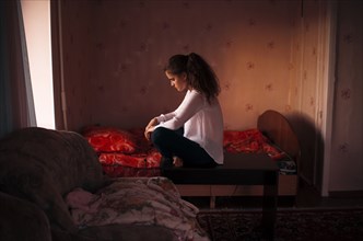 Caucasian woman sitting in bedroom
