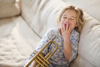 Caucasian girl sitting on sofa with trumpet