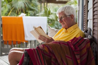 Caucasian man reading on porch