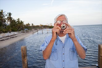 Caucasian man taking photographs on beach
