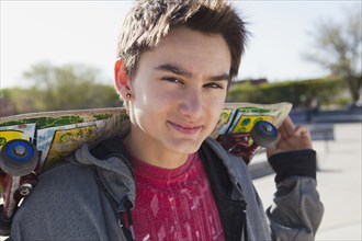 Smiling mixed race boy holding skateboard