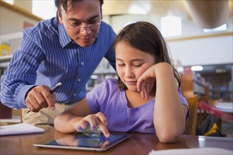 Teacher helping student use digital tablet