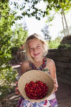 Caucasian girl holding basket of cherries