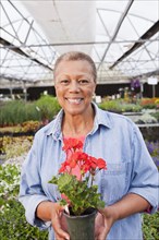 Mixed race woman holding flower in plant nursery