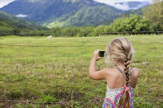 Caucasian girl taking photograph of rural meadow