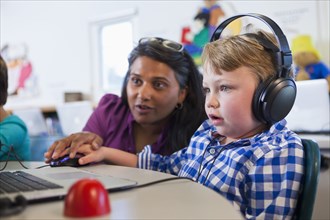 Teacher helping student using laptop
