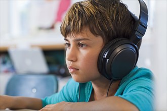 Mixed race student listening to headphones in classroom