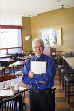 Hispanic cafe owner holding clipboard