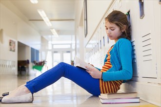 Caucasian student reading in school hallway