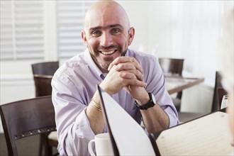 Mixed race businessman smiling in cafe