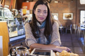 Mixed race woman using tablet computer in coffee shop
