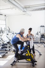 Older Hispanic man working with trainer in gym
