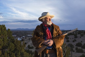 Caucasian man holding gun in dusty landscape