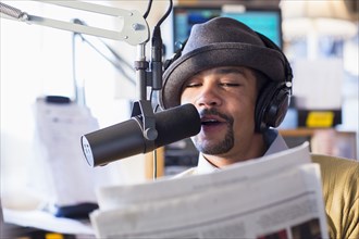 Mixed race disc jockey talking into mic in studio