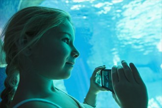 Caucasian girl taking pictures in aquarium
