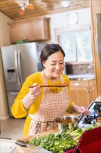 Mixed race woman cooking in kitchen