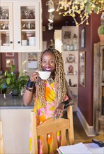 African American woman having cup of coffee in kitchen