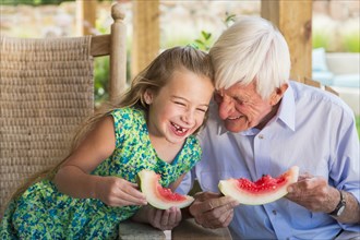 Caucasian man and granddaughter eating watermelon