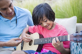 Father teaching son to play guitar outdoors