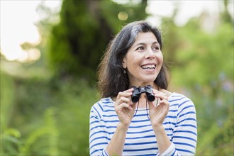 Hispanic woman using binoculars outdoors