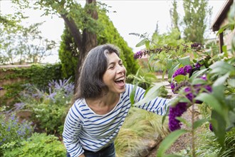 Hispanic woman looking at flowers in garden