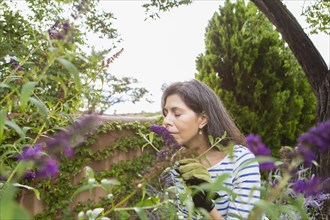 Hispanic woman smelling flowers in garden