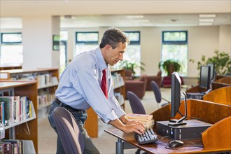 Senior man working on computer in library