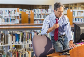 Senior man working at computer in library