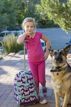 Caucasian girl with suitcase and dog outdoors
