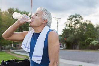 Hispanic man drinking water in park