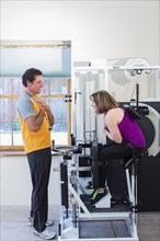 Caucasian woman working with personal trainer in gym