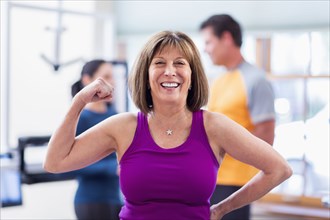 Caucasian woman flexing her muscles in gym