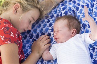 Caucasian girl laying with newborn baby brother