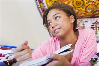 Mixed race teenage girl doing homework in bedroom