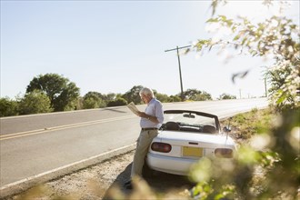 Senior Caucasian man reading map by road