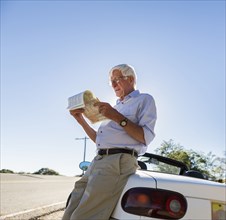 Senior Caucasian man reading map by road