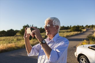 Senior Caucasian man taking pictures with cell phone
