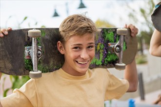 Caucasian boy holding skateboard outdoors