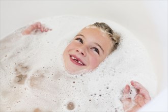 Caucasian girl laying in bubble bath