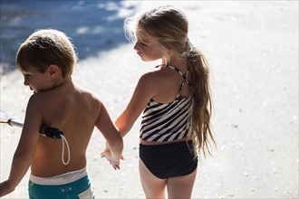 Children in swimsuits holding hands outdoors