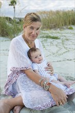 Mother cradling newborn boy on beach