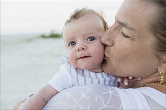 Mother kissing baby on beach