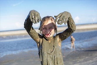 Caucasian girl playing in mud on beach