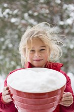 Caucasian girl holding bowl in snow