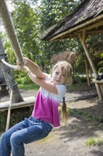 Caucasian girl hanging on ropes outdoors