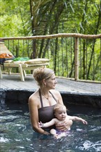 Caucasian mother and baby relaxing in pool