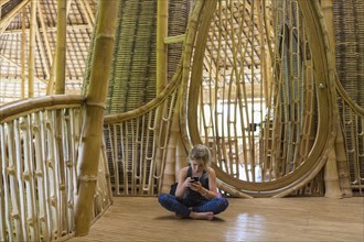 Caucasian girl using cell phone in bamboo house